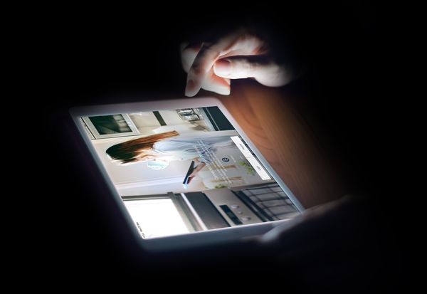 Close-up of a woman using the Home Connect app on a tablet at night 
