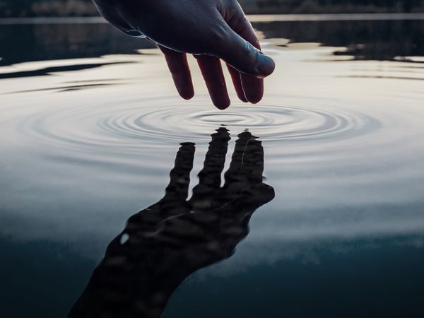 A hand making ripples in the water 