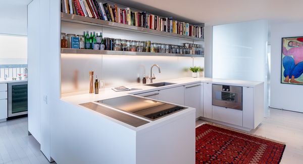 Cookbooks and spices lining shelves above the sleek white counters of the Spy House. 