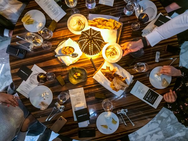 A top-down view of a dinner table at a Club 1683 event. Guests enjoying fine wine and appetizers. 