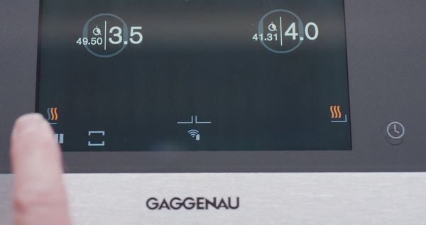 An image showing a hand interacting with a Gaggenau induction cooktop TFT display
