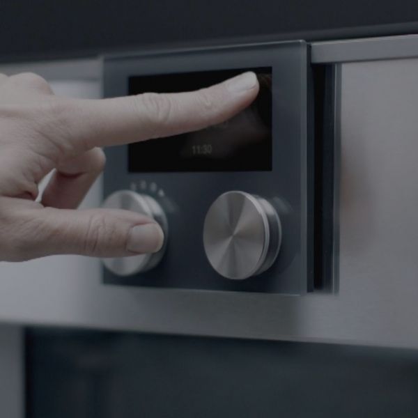 En finger som trykker på den interaktive skjermen til en Gaggenau-stekeovn i 400-serien