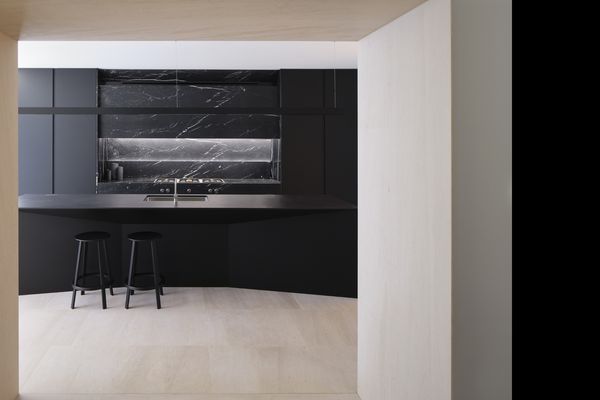 View from adjoining room of a luxury dark kitchen with island worktop