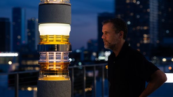 Against the Miami evening skyline, Matt Gagnon is illuminated by light from his sculpture.