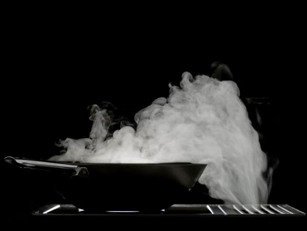 Dark backlit image of a Gaggenau 400 series downdraft ventilation unit extracting steam efficiently away from a wok
