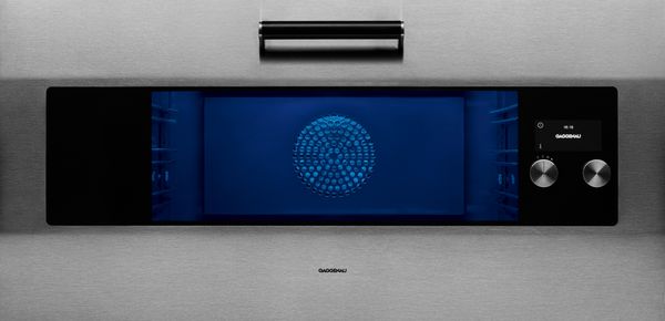 Close-up view of a Gaggenau EB 333 oven with the interior lit in blue light 