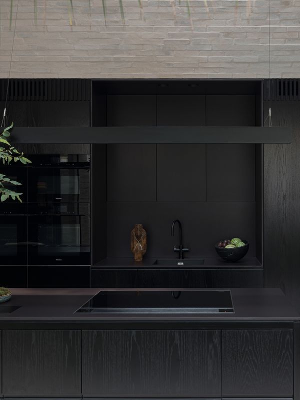 The kitchen area of the Victorian terrace Vessel with it’s pale brick floors, walls and ceilings and the black, masculine timber worktops with Gaggenau appliances.