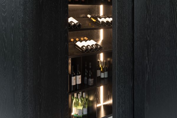Dark timber wine storage area with complimentary lighting.