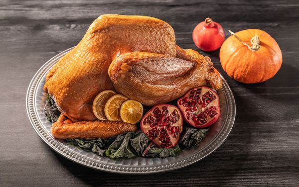 Roast Heritage turkey on a platter garnished with Pomegranate and Pumpkin