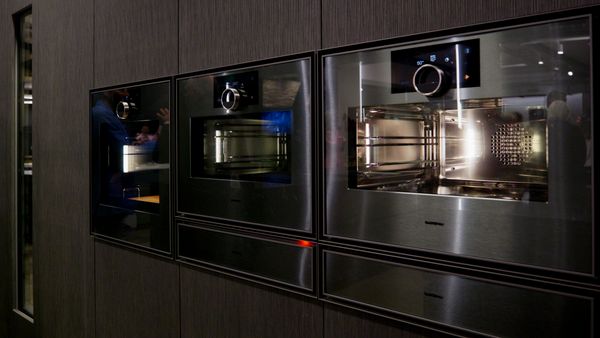 A close-up of sleek, handleless, black built-in wall ovens.