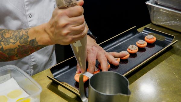 A chef in a white uniform prepares food at a kitchen counter.