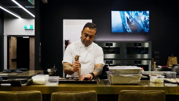 A chef with tattooed arms pipes filling onto small appetisers.