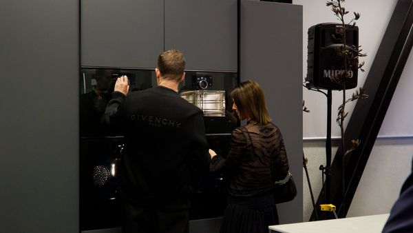 A couple examines the features of a modern, dark oven.
