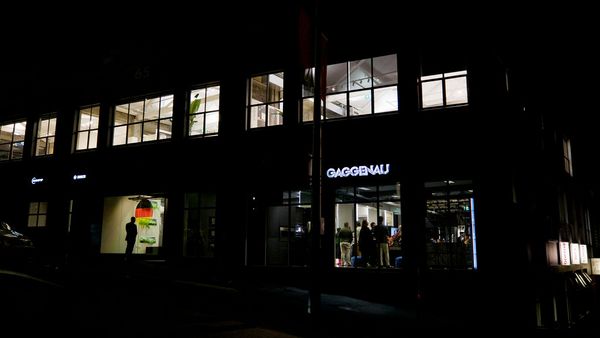 Exterior night shot of a modern building with "Gaggenau" illuminated on its facade.