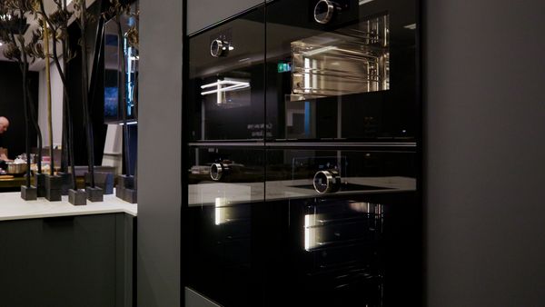 A row of three modern, stainless steel built-in wall ovens.