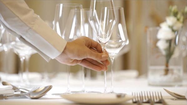 Waiter setting a formal dinner table  