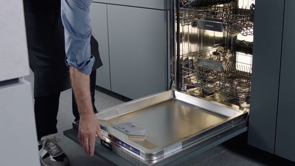 Man opening a Gaggenau 400 series dishwasher in a modern kitchen 