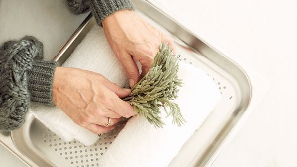 Windsor Smith placing sage with hand towels to steam in her Gaggenau Combi-steam oven