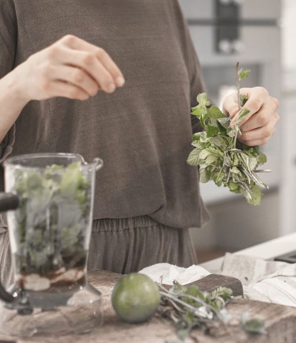Woman preparing herbs on kitchen surface 