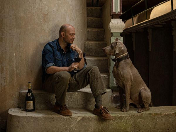 Image of Elías López Montero drinking wine with his dog