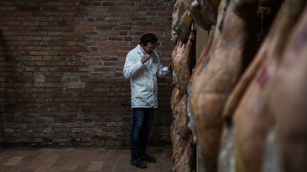 Image of Stefano Bettella testing the hanging legs of ham