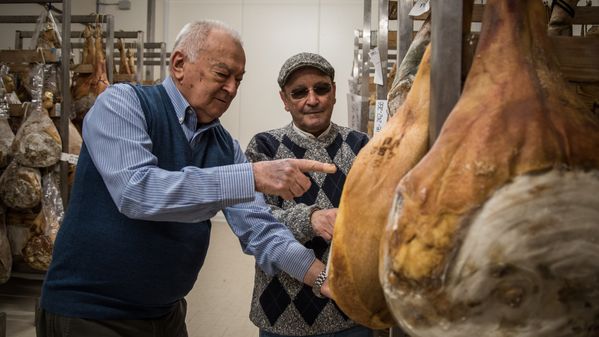 Image of two men inspecting the legs of ham