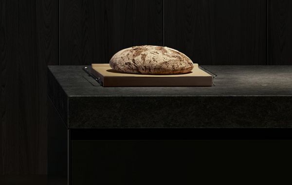 Kitchen worktop with a Gaggenau baking stone under a loaf of bread 