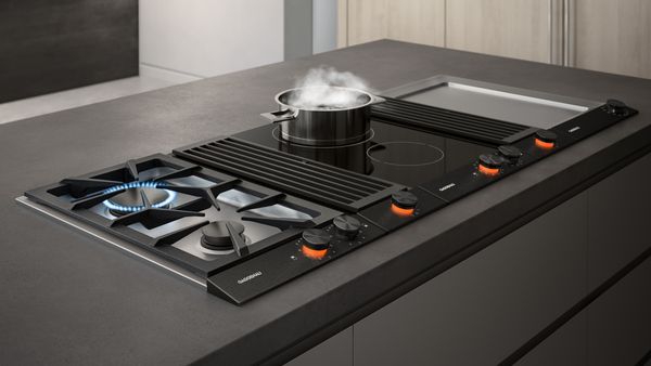 A Gaggenau cooktop featuring gas, induction, a teppanyaki grill, and downdraft ventilation. 