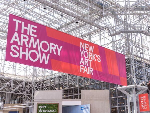 A large, colorful banner for The Armory Show hanging from industrial rafters. 