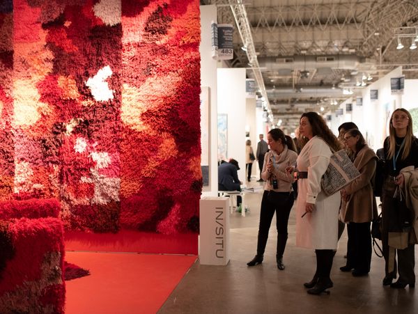 Guests admiring a large installation made of bright red fibers. 