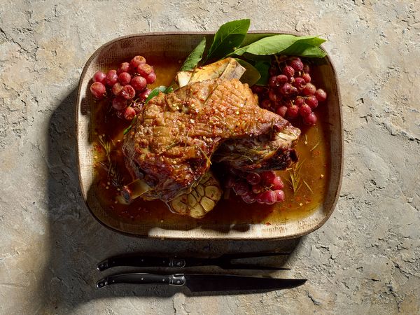 Slow roasted lamb shoulder with red grapes on a serving dish