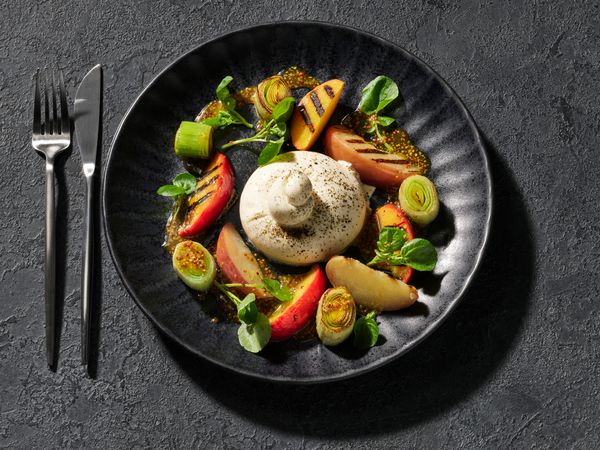 Grilled peach salad with leek and burrata in a bowl