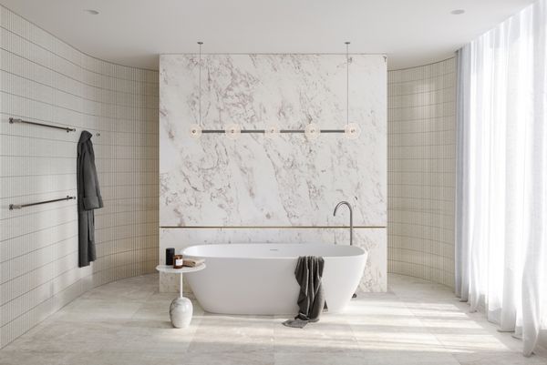 Luxury bathroom finished in light stone materials with free-standing bath