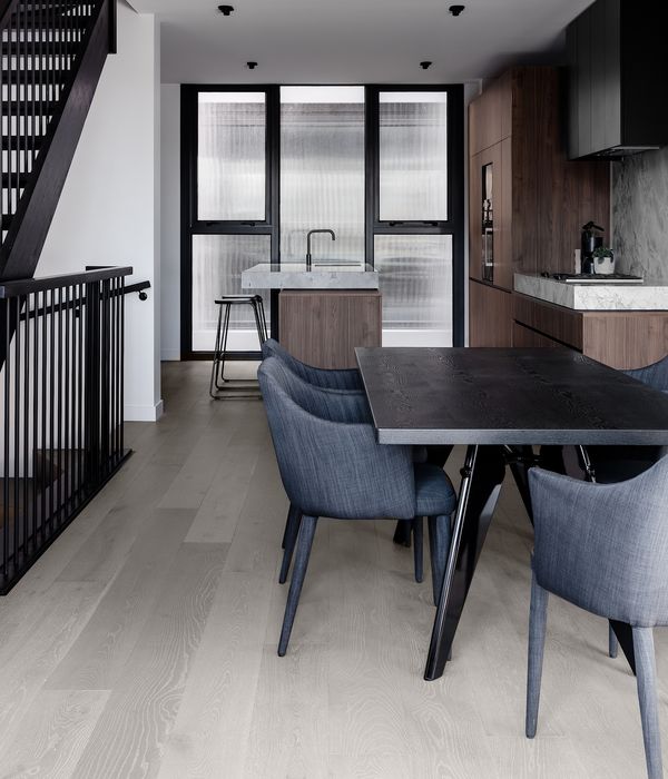 View looking across dining area and onto a light grey and wood luxury kitchen.