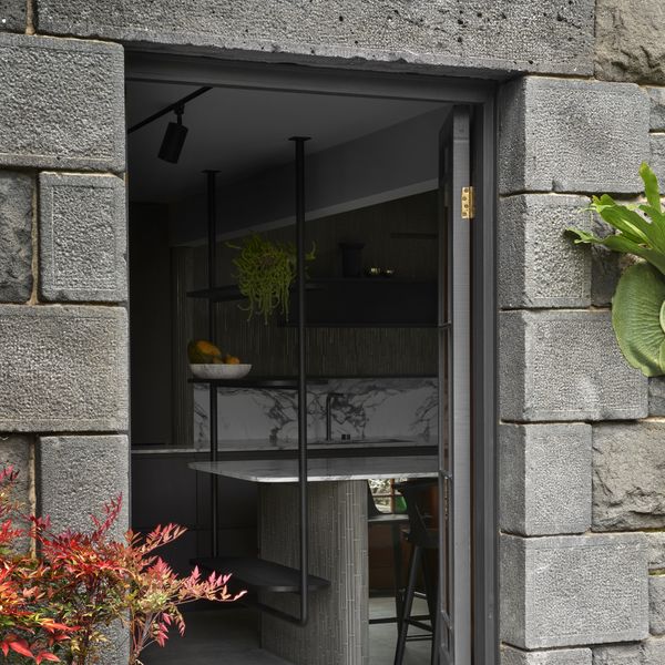 External view looking through an open door into a luxury dark kitchen with island worktop