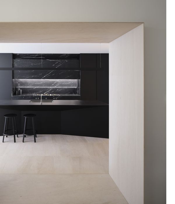 View from adjoining room of a luxury dark kitchen with island worktop