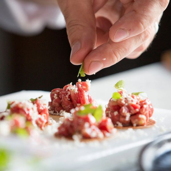 Close-up of Chef Romuald Oudeyer putting the finishing touches to a dish of starters