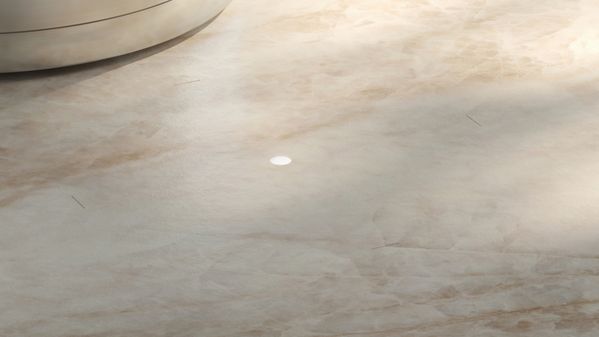 A small light mounted within a marble-like material indicates the state of the unseen induction cooktop