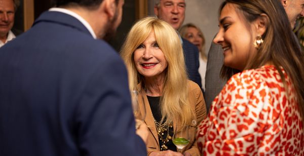 Sally Forster Jones, smiling and shaking hands with other guests. 