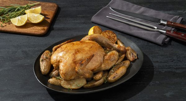 Serving plate containing a roast chicken with shallots and fingerling potatoes