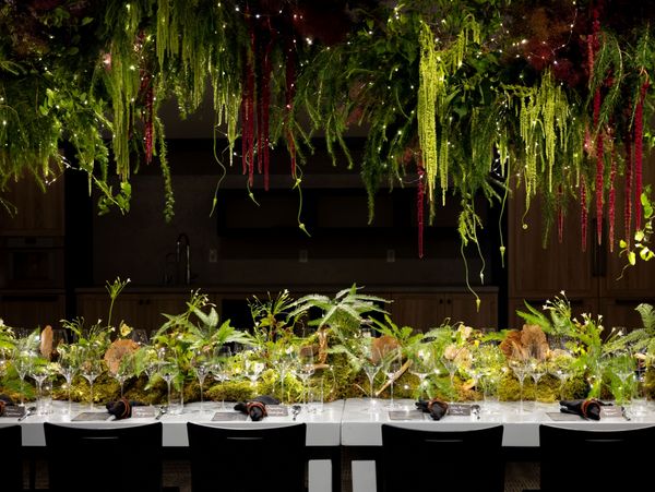 The elegant tablescape for the event, draped in moss and greenery to simulate a forest. 
