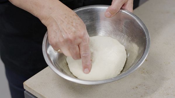 Chef Larissa kneads dough on a stainless steel bowl