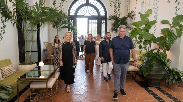 Guests, including Erica Zohar and Thomas Yianilos, entering the venue, which is beautifully decorated with lush green plants.