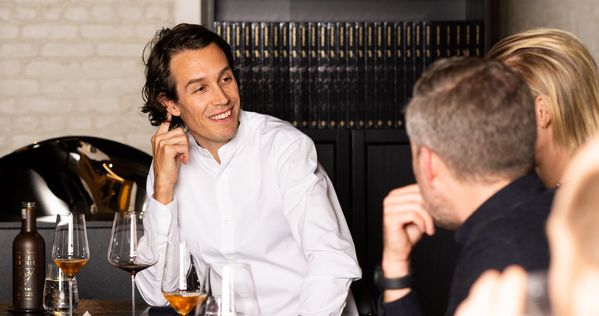 Chef Fredrik Berselius smiling as he converses with guest chefs at the table.