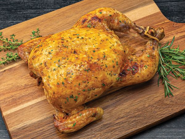 A delicious roast chicken resting on a wooden chopping board