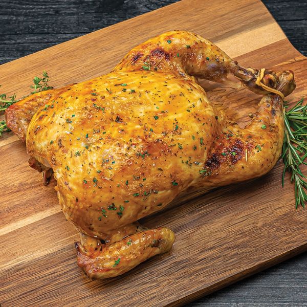 A delicious roast chicken resting on a wooden chopping board