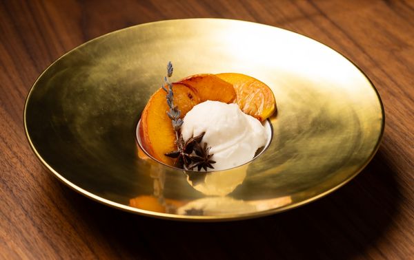Poached nectarines with brunost ice cream arranged on a golden Hering Berlin dish. 
