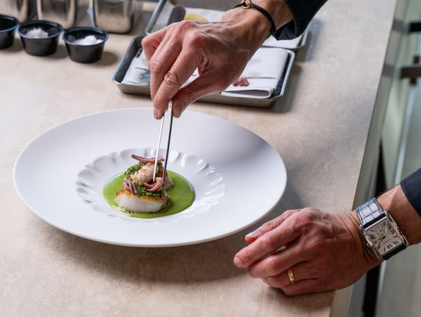 A Black Jacket Society chef carefully plates a beautiful seafood dish.