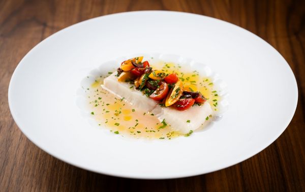 Steamed halibut with tomato consommé and sauce vierge arranged on a Hering Berlin dish. 