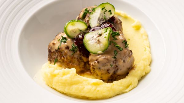A close-up of meatballs on a bed of potato purée. 